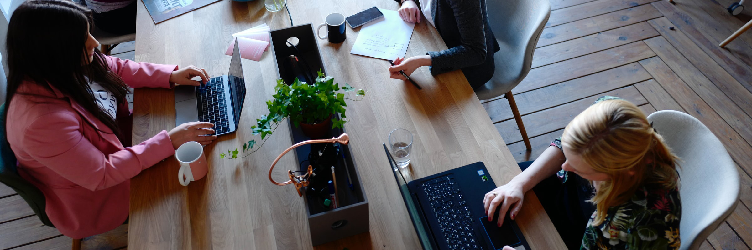Cover picture Resonance Analysis The picture shows a long table at which two women sit opposite each other and work on their laptops.
